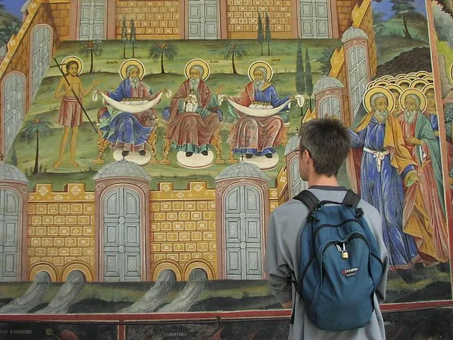 Tourist looking at the detailed and vibrant frescoes on Rila Monastery's exterior walls