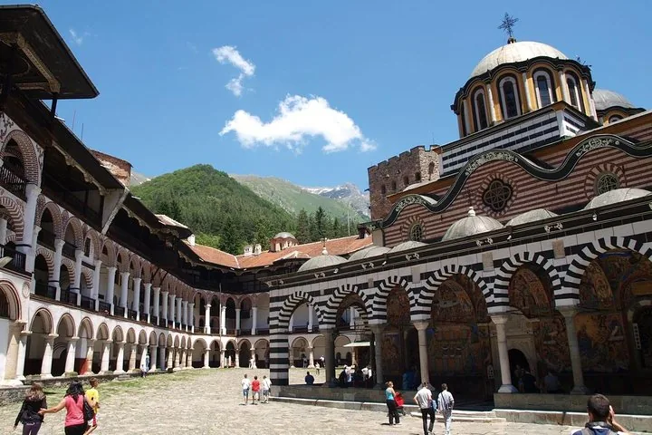 People walking around the courtyard of Rila Monastery on a sunny summer day