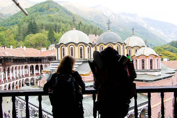 Hikers looking out over the domes and courtyard of Rila Monastery